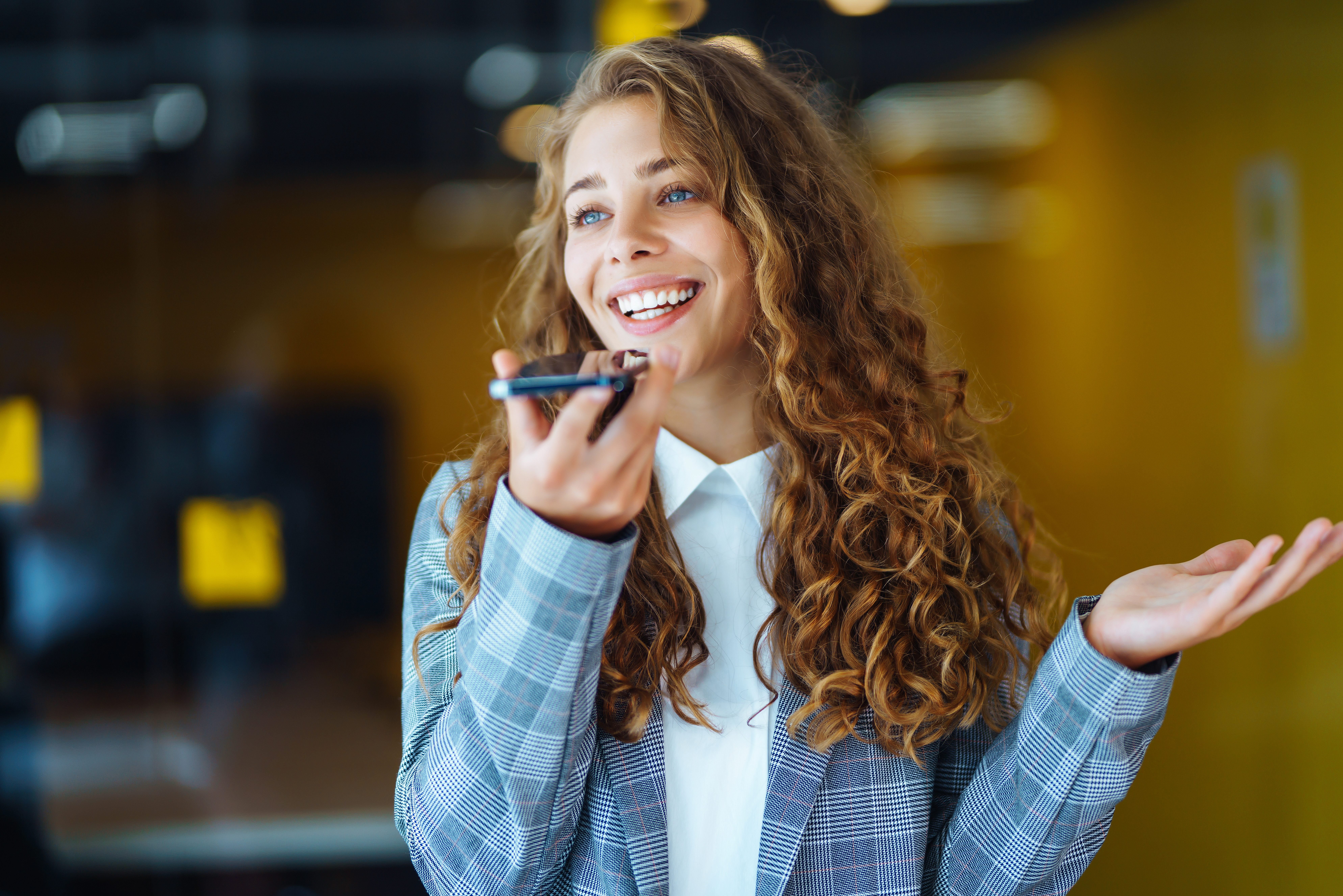 A woman smiling while talking on her smartphone.